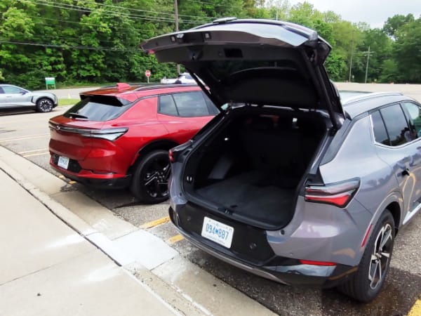 Two small SUVs parked, viewed from rear-quarter angle, rear hatch is open on one on right.