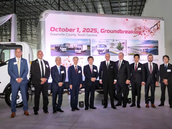 Group photo of men in suits standing in front of a box truck.