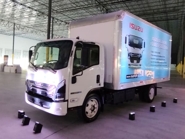 A medium-duty electric box truck is on display inside a building.