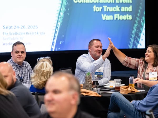 Fleet managers and suppliers high-fiving and laughing during an outdoor networking activity at Work Truck Exchange 2025.