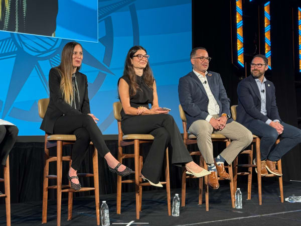Five panelists deliver a seminar on stage. 