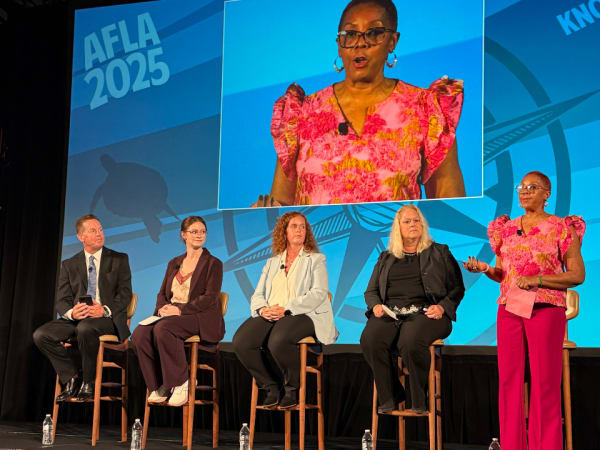 Five panelists deliver a seminar on stage. 