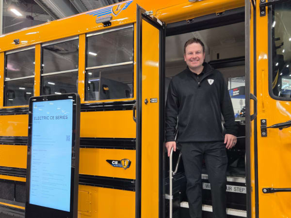 Alec Borror stands in the doorway of an IC Bus electric CE Series school bus displayed on the ACT Expo show floor.