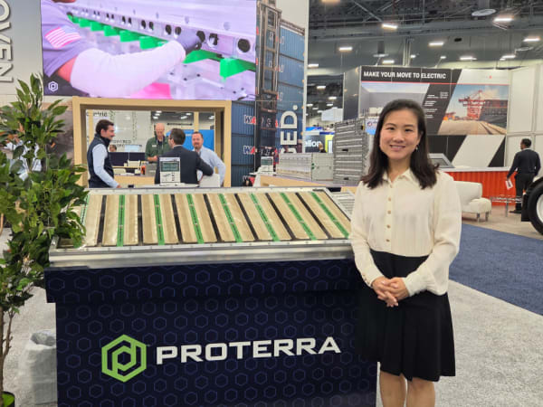 A Proterra representative stands beside the company’s commercial EV battery technology exhibit at ACT Expo 2026.