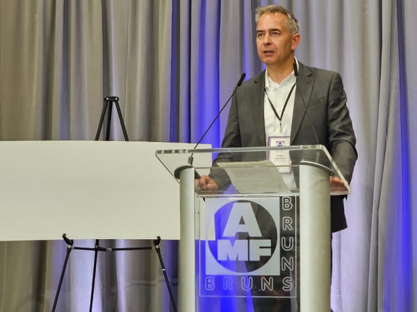 AMF Bruns CEO speaks at podium during grand opening ceremony
