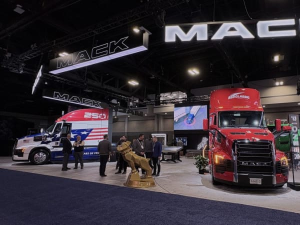 wide angle photo of trade show booth with big "Mack" sign above, red Mack truck in the foreground