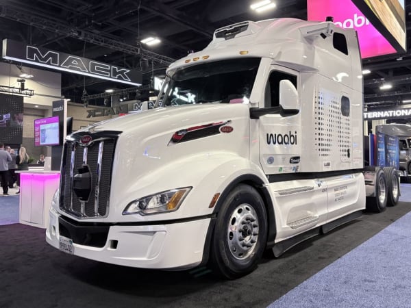 White Peterbilt truck with the name Waabi on the side and visible sensor pods in front of the grille and on top of the cab