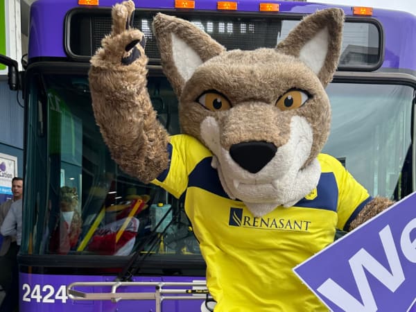 Nashville SC mascot poses in front of a purple WeGo Transit bus.