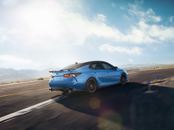 A blue 2021 Toyota Camry driving on the road