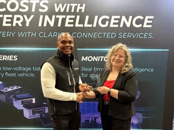 Man and woman shaking hands with Top 20 trophy between them