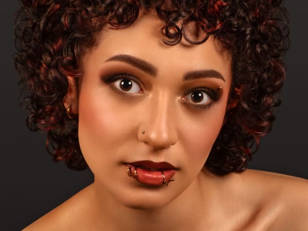 A model with piercings and very curly hair
