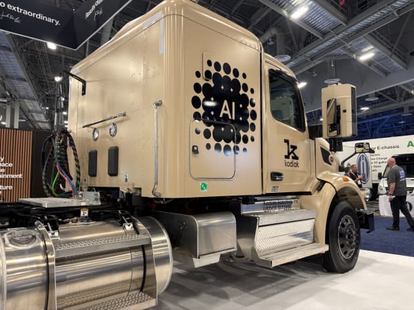 Khaki colored semi tractor on exhibit floor with "AI" graphic on the side
