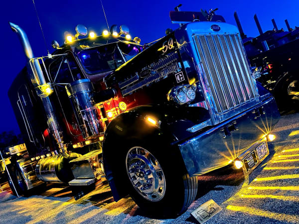 Dark colored Peterbilt vintage trucks with colorful accent lights at night
