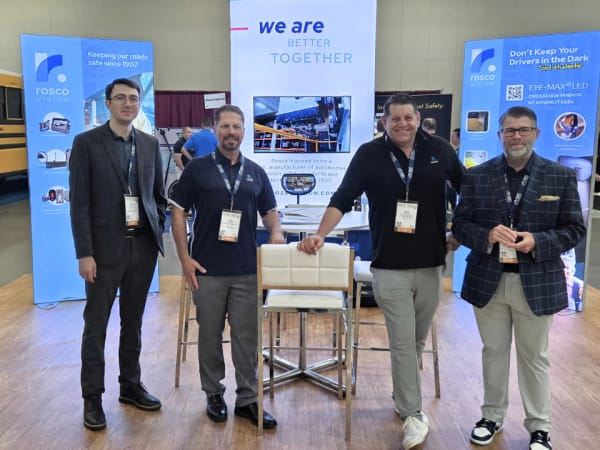 Four Rosco Vision Systems representatives pose at their NAPT ACTS 2026 exhibit, surrounded by displays highlighting school bus mirrors and safety technology.