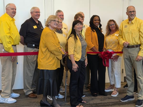 NAPT leaders and members gather for a ribbon-cutting ceremony at ACTS 2026 in Louisville, posing behind a red ribbon with a large bow.