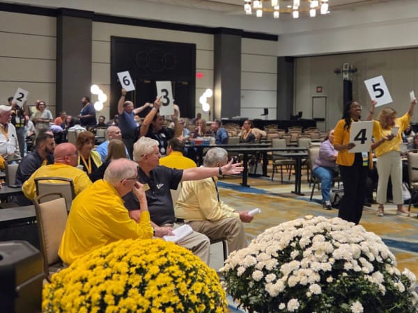 Attendees at NAPT ACTS 2026 in Louisville participate in an interactive trivia activity, raising numbered signs and engaging with a presenter during a conference session.