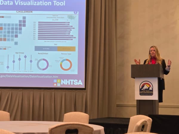 Michelle Atwell of the National Highway Traffic Safety Administration presents federal school bus safety updates on a stage at the NSTA event