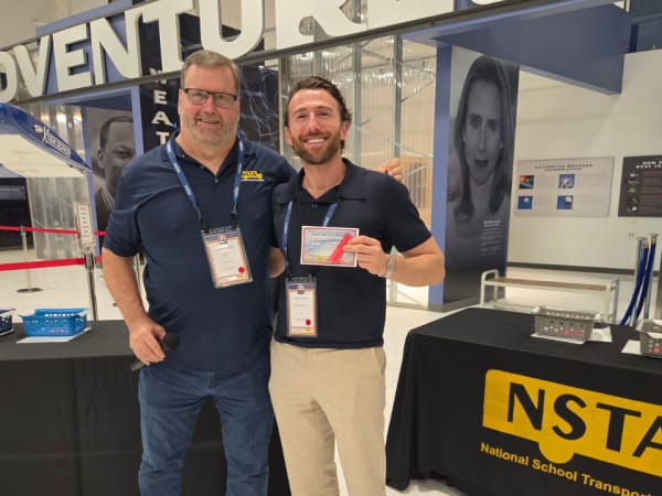 Isaac Linson, CEO of BusesForSale.com, poses with Curt Macysyn after winning the conference's Tricky Tray auction at Wings Over the Rockies.