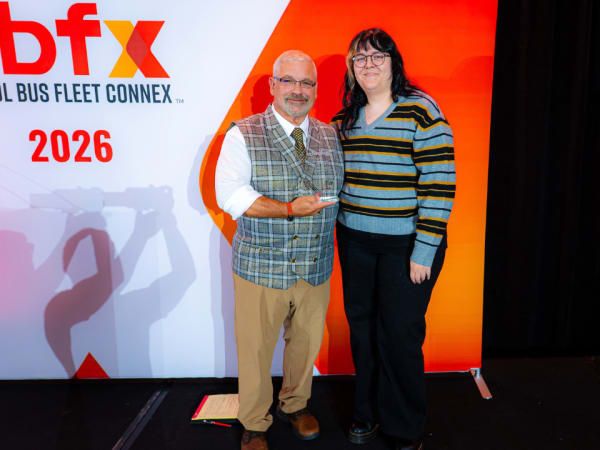 Sam Freshner holds Kathy Calkins' 2026 School Bus Fleet Administrator of the Year award at School Bus Fleet Connex.