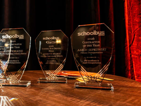 Trophies for School Bus Fleet's 2026 Special-Needs School Bus Driver of the Year, Administrator of the Year, School Bus Driver Hero, and Contractor of the Year awards displayed on a table.
