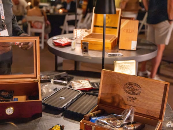 Open cigar boxes and accessories are displayed on tables during an evening networking event at School Bus Fleet Connex.