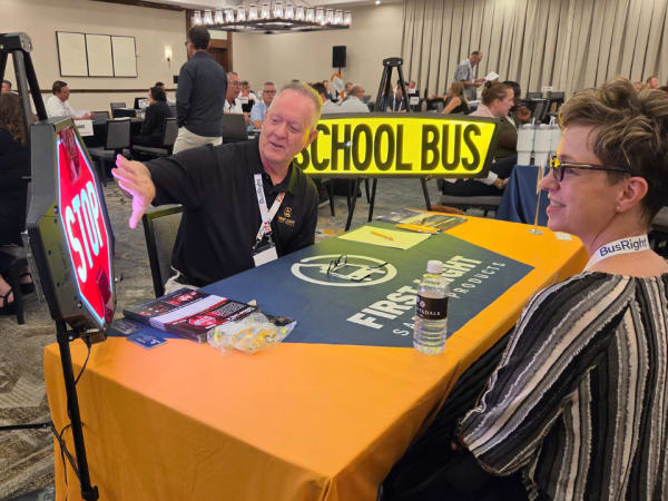 A First Light Safety Products representative demonstrates illuminated school bus stop and school bus signs during a one-on-one meeting at School Bus Fleet ConneX.