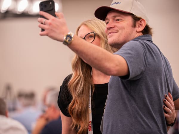 Two School Bus Fleet ConneX attendees smile while taking a selfie together during the event.