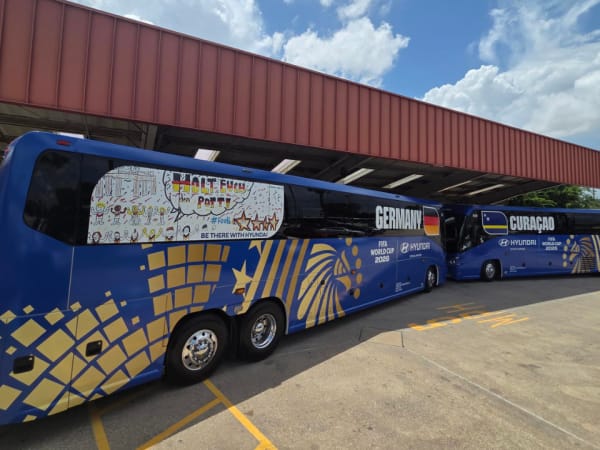 World Cup-wrapped First Class Transportation motorcoaches for Germany and Curaçao sit staged during the tournament.