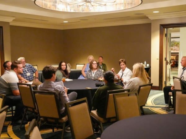 12 attendees talk around a conference table. 
