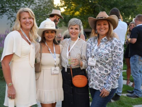 Four women standing at an outdoor reception pose for camera. 