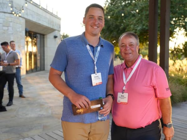 Winning golfer poses with host outside.