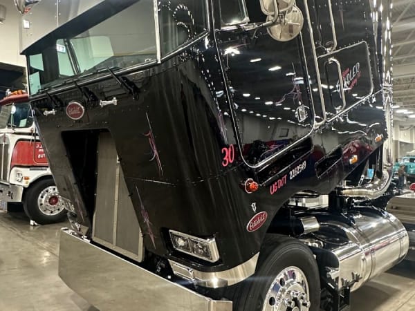 Black Peterbilt cabover with cab tilted forward to reveal engine