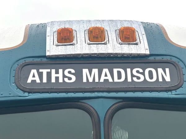 Antique bus with destination sign above windows saying ATHS Madison