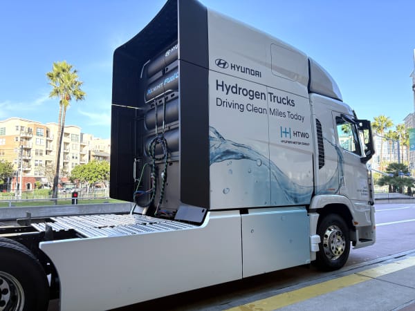 White Hyundai Xcient FCEV cabover outside convention center from side/rear view