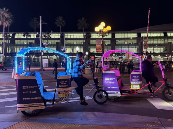 Colorfully lit pedicabs wait for customers near the convention center