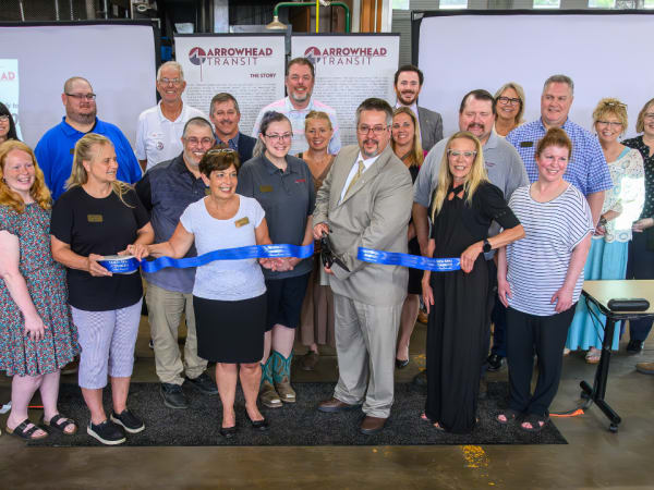 Business and community members pose during a ribbon cutting.