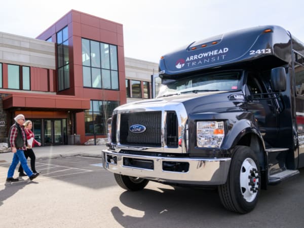 A couple walks toward an Arrowhead Transit bus.