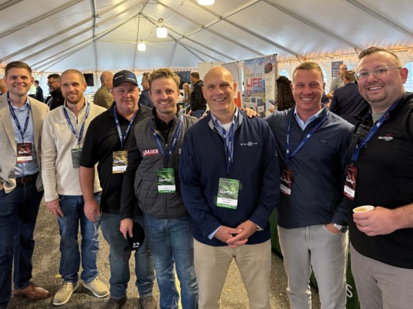 Group gathers for photo in exhibitor tent. 