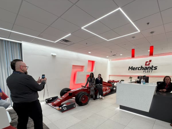 Attendees pose for photo on race car in HQ. 