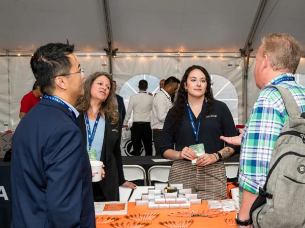 Attendees gather around an exhibit table. 