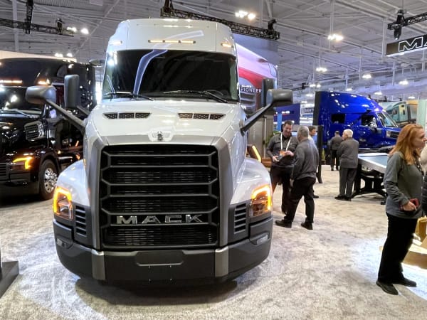 White Mack Pioneer truck at booth with other trucks and people in background