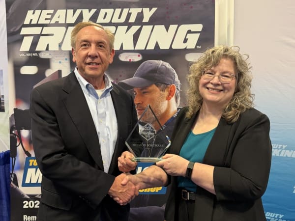 Man and woman shaking hands with Top 20 trophy between them