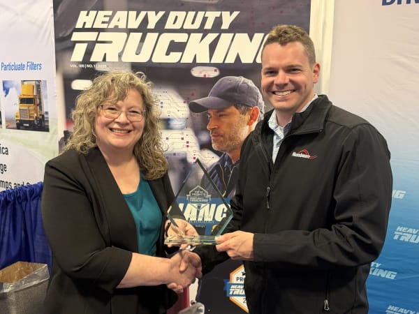 Man and woman shaking hands with Top 20 trophy between them