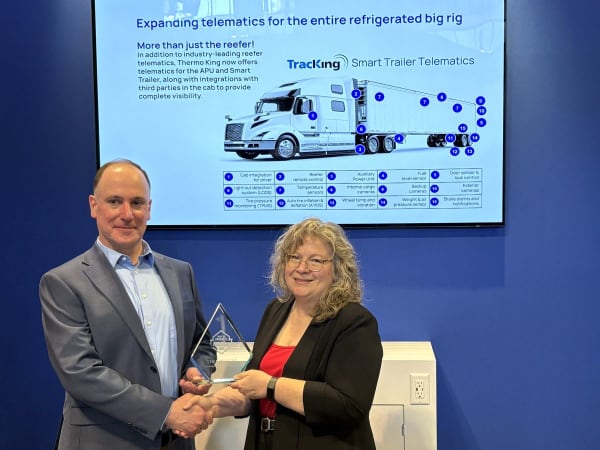 Man and woman shaking hands with Top 20 trophy between them