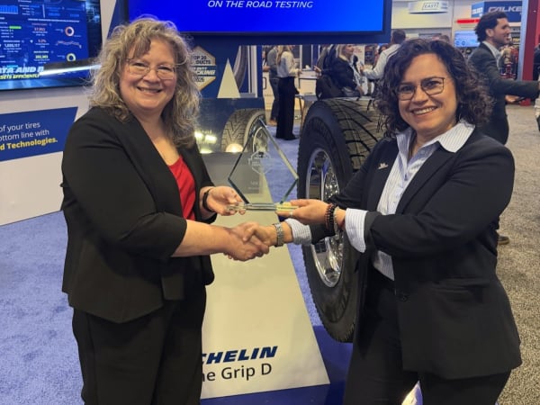 Two women shaking hands with Top 20 trophy between them