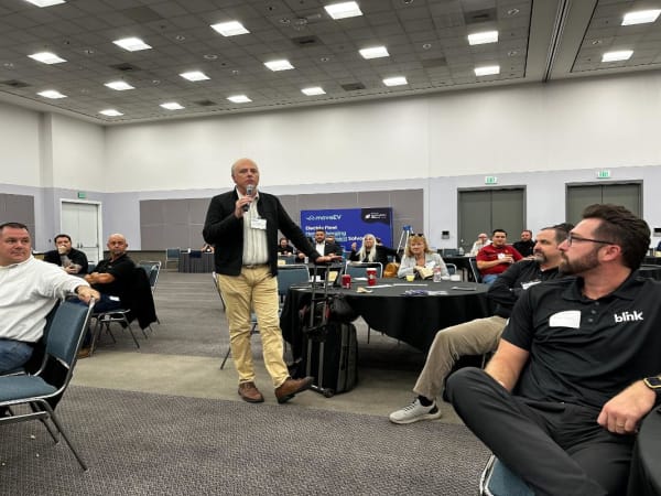 Photo of man with microphone in audience asking a question during a seminar at LA Auto Show. 