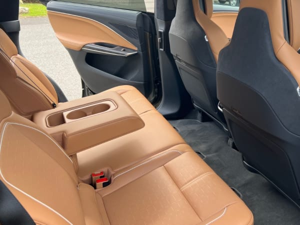 Ride side view of two rear passenger seats separated by armrest with two cupholders.