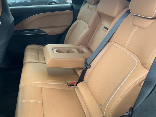 Left side view of two rear passenger seats separated by armrest with cupholders.