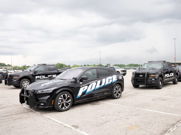 Three black upfitted Ford pursuit-rated vehicles are lined up in a parking lot.