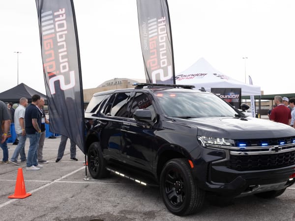 A black Chevrolet Tahoe PPV is shown with blue lights flashing from the grille.